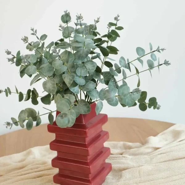 Dekoracyjny biały wazon z trzema wylotami, z którego wychodzą gałązki kwiatów wiśni