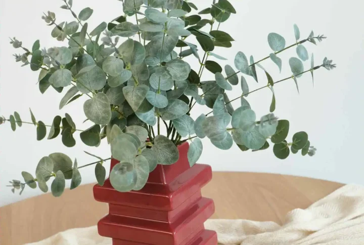 Dekoracyjny biały wazon z trzema wylotami, z którego wychodzą gałązki kwiatów wiśni